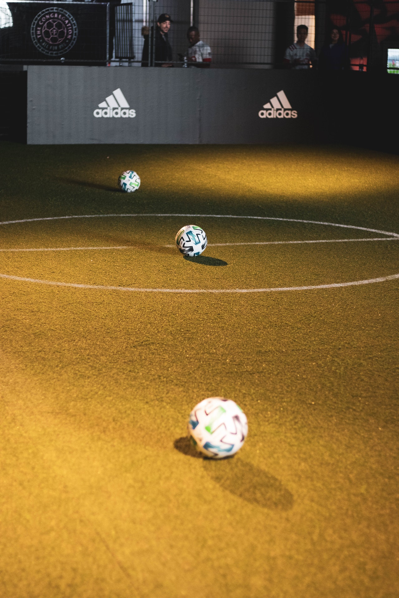 synthetic turf pitch with 3 football balls on it
